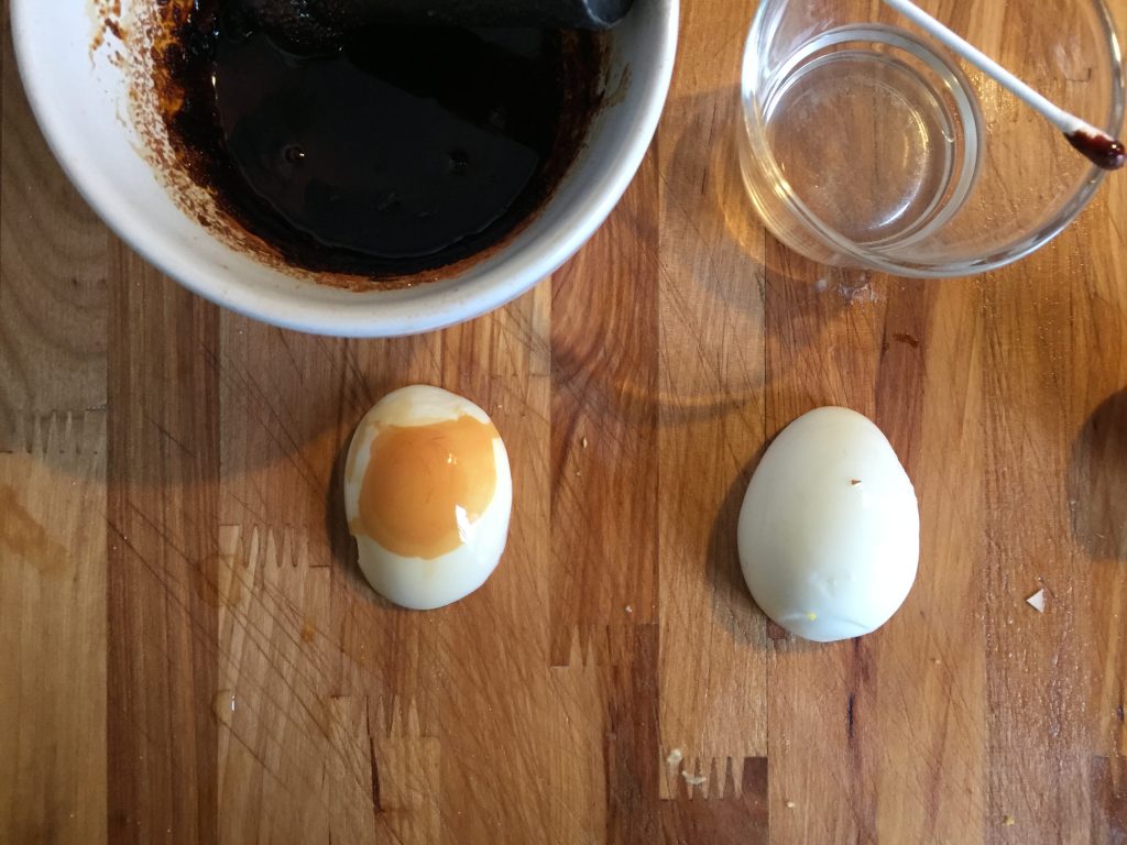 Photo of two peeled white eggs, the one on the left has a big light brown stain, the one on the right is completely white