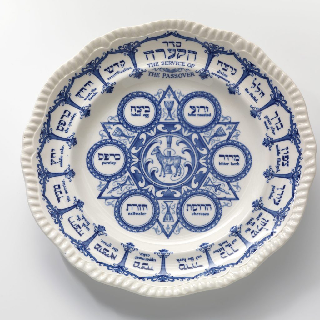 Historischer Seder-Teller. Blaue Beschriftungen in hebräisch und englisch auf weißem Grund.